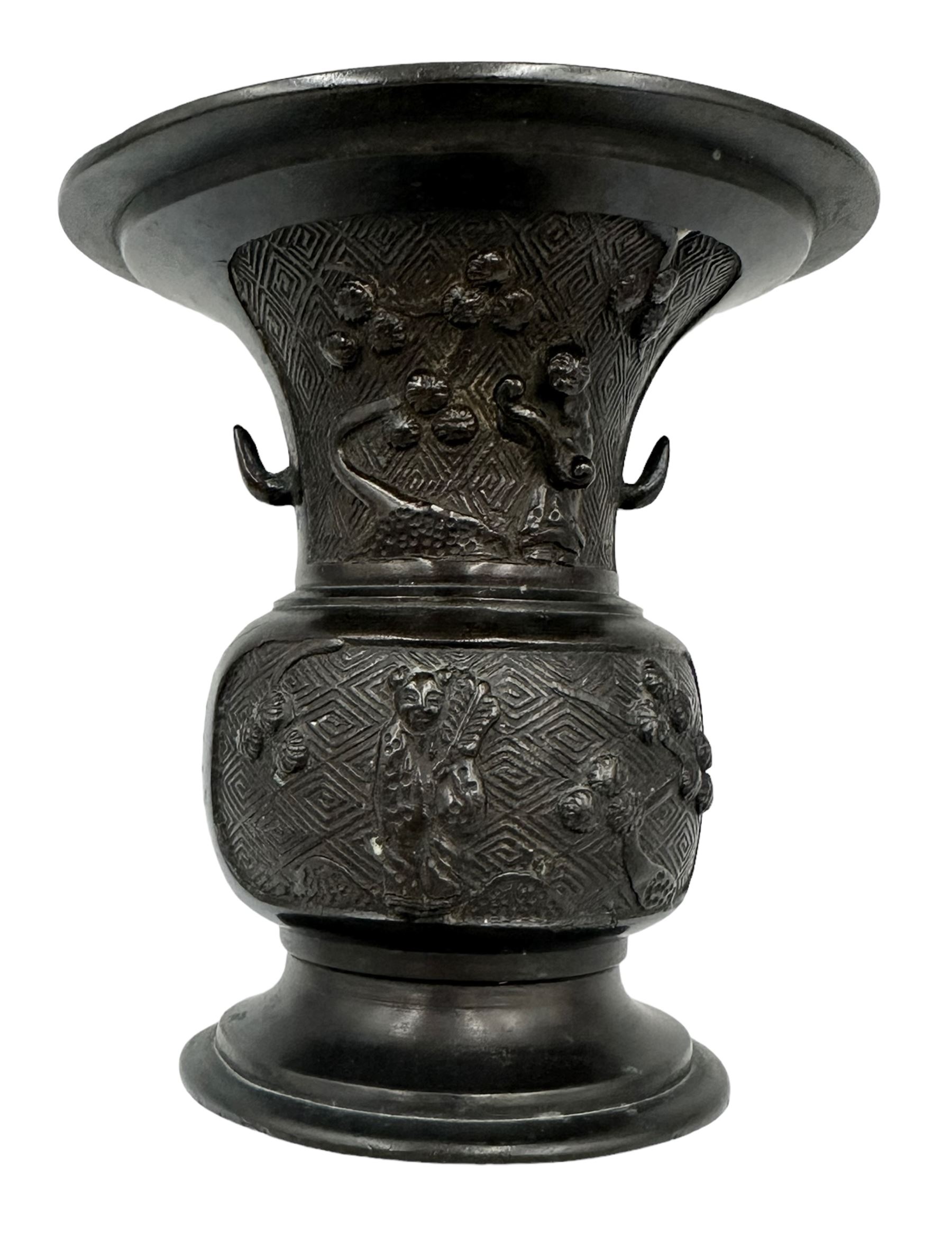 Chinese bronze gu vase decorated with a raised pattern of flowering branches, figures holding book, scrolls and fan on a circular foot H13cm