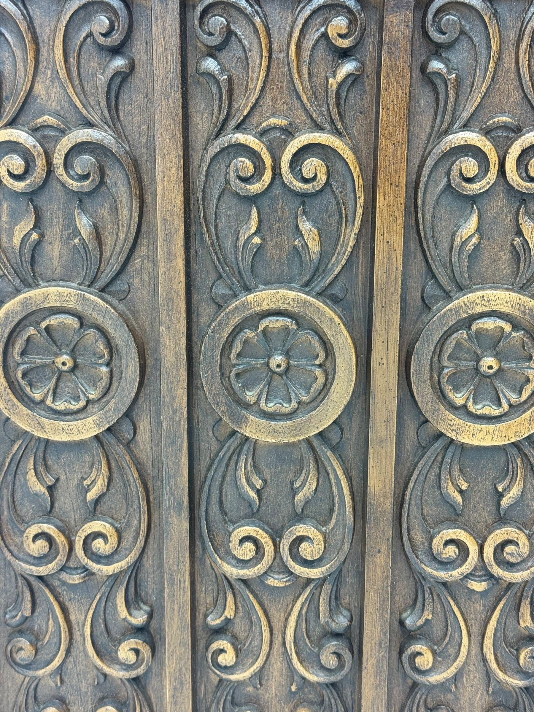 Mid 20th century oak bookcase cupboard, projecting cornice over three open shelves with subdivided sections and latticework uprights, two doors to the base with floral and scrollwork carvings and central brass handles, resting on a moulded plinth base