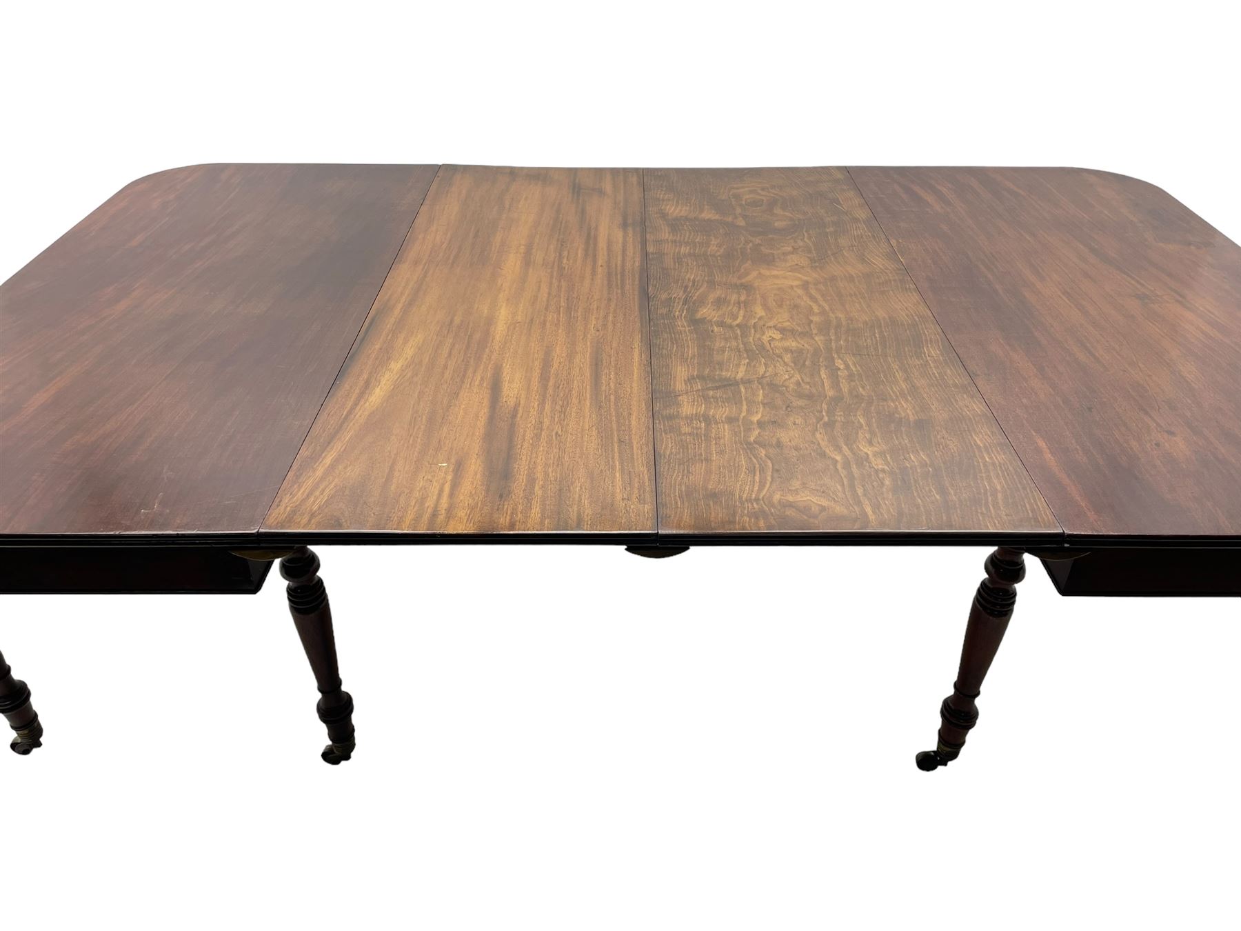 George III mahogany extending dining table, reed moulded rectangular top with rounded corners, two D-ends each fitted with two drawers, two additional leaves, on turned supports with ribbed brass cups and castors 