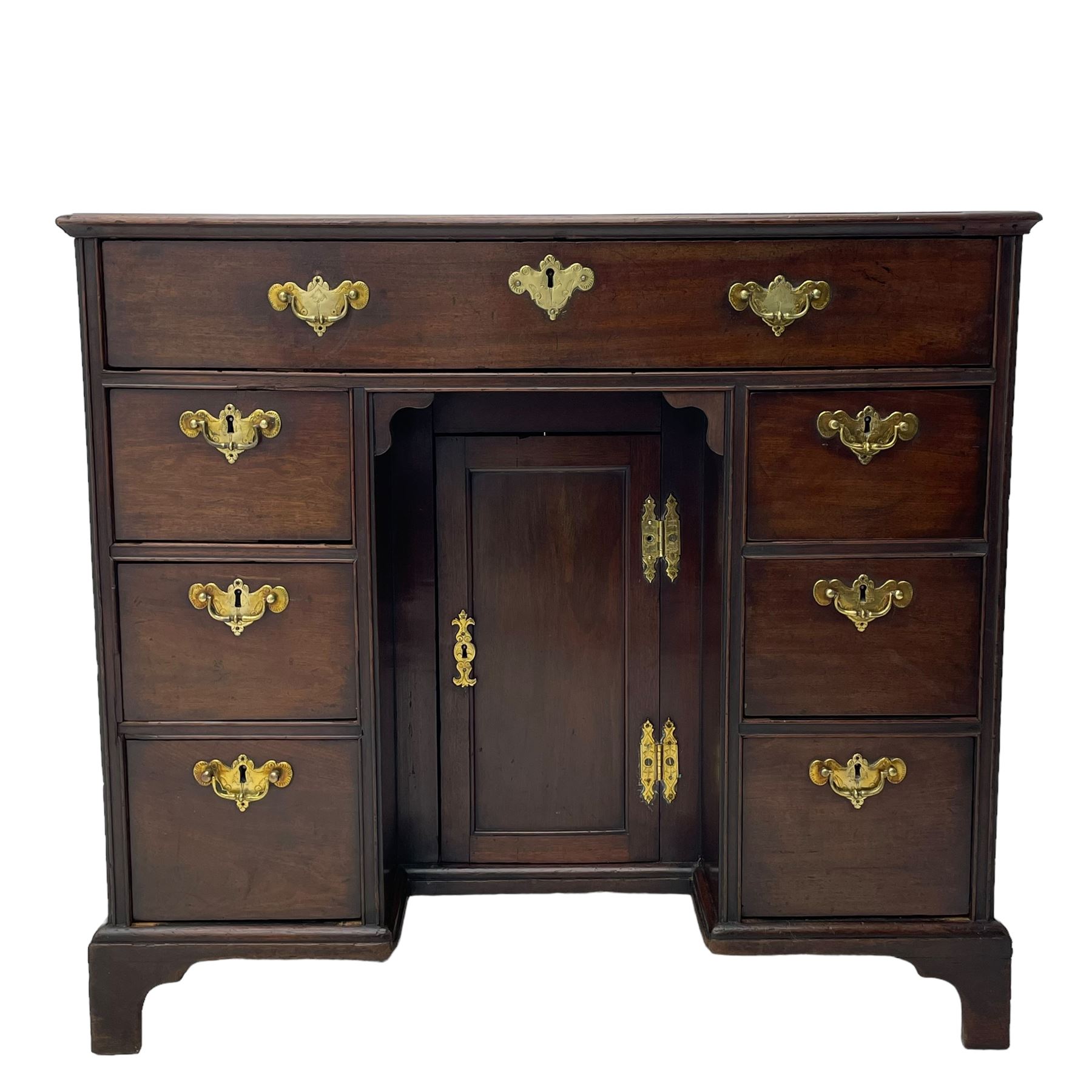 George III mahogany kneehole desk, moulded rectangular top over one long drawer, six short drawers and recessed panelled cupboard, cock-bead moulded frame, fitted with shaped brass handle plates with engraved decoration, on bracket feet 