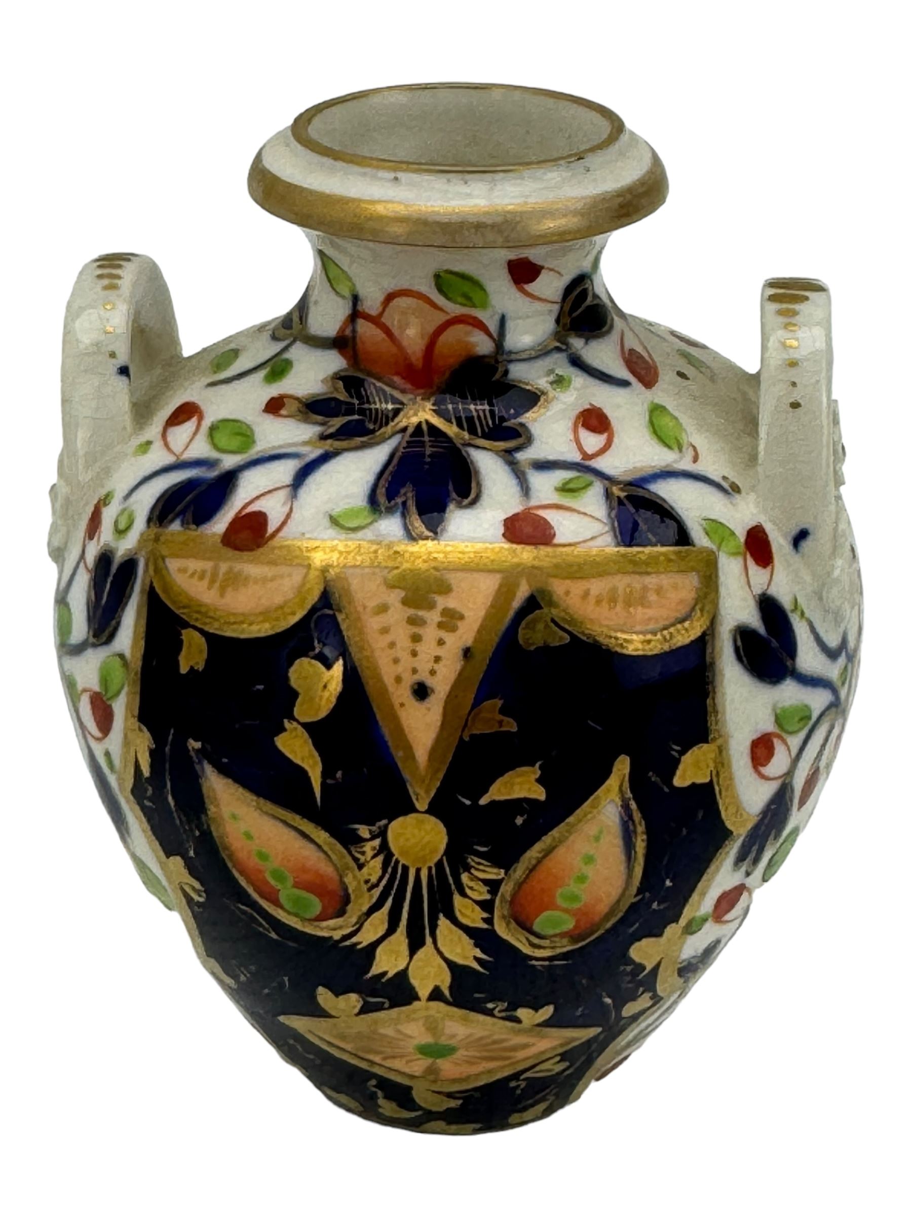 Early 19th century Derby porcelain to include a campana form inkwell, small bottle form vase, twin handled vase and flared rim vase, hand painted with a landscape scene, H10cm (4)