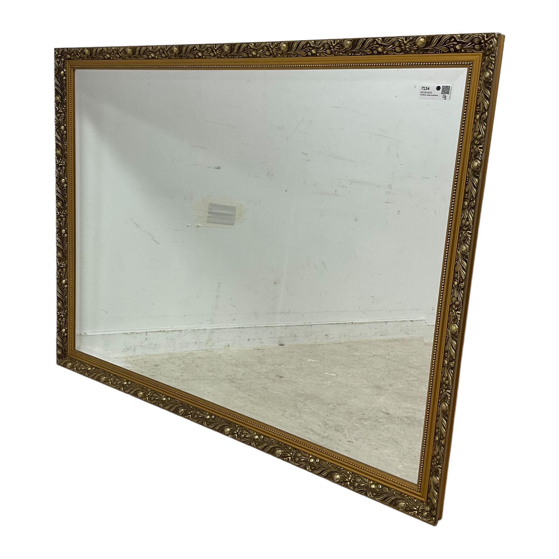 Large rectangular gilt framed wall mirror, decorated with trailing leafy branches and flowerheads, bevelled glass plate 