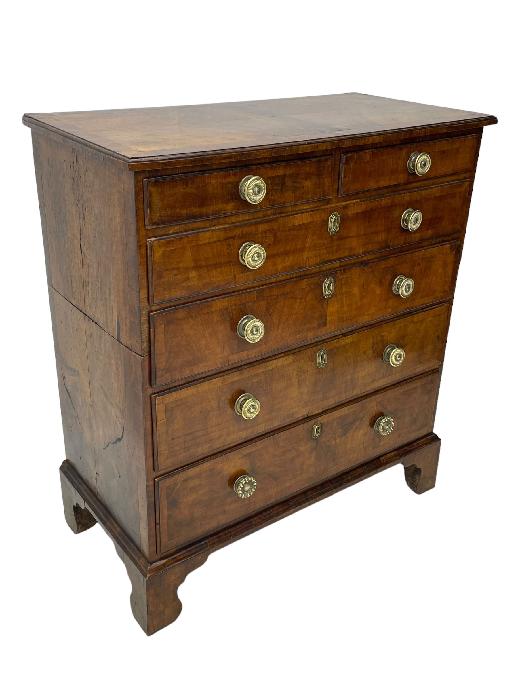 George I walnut chest, moulded rectangular top with book-matched veneers within crossbanding, fitted with two short over four long graduating drawers, moulded drawer fronts with brass handles, on bracket feet, the chest will split into two sections 