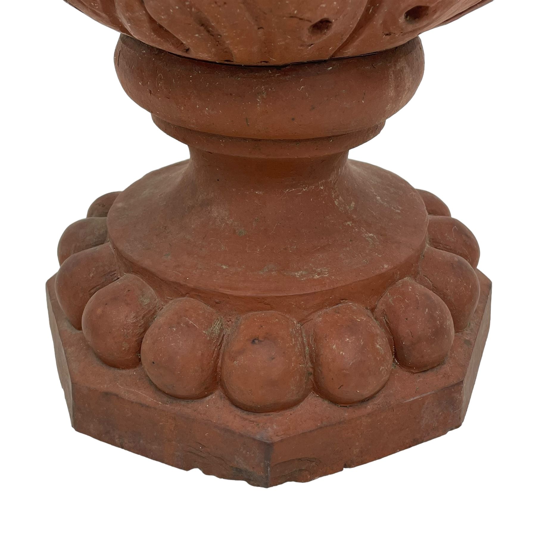 Pair of late 19th to early 20th century red terracotta garden urn planters, the shallow bowls moulded with curled acanthus leaf decoration, on circular foot with globular beaded moulding, octagonal base