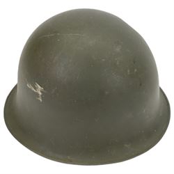 Collection of nine military helmets, including several with camouflage covering 