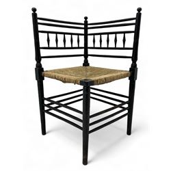 In the manner of William Morris - Arts & Crafts period corner chair, swell turned horizontal rails with balustrade back, rush seat on ring turned supports, black paint finish 