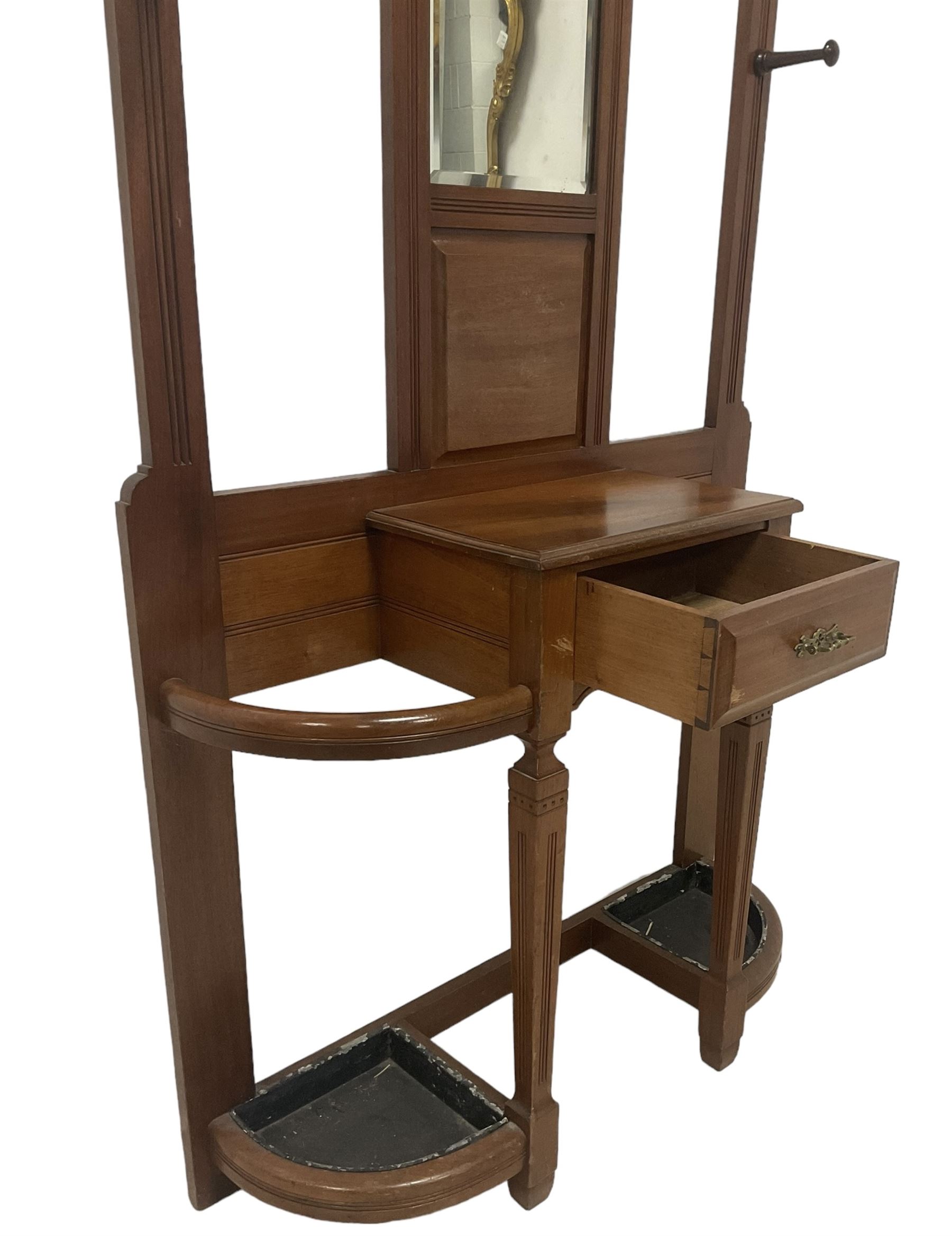 Late Victorian hallstand, raised pediment over balustrade frieze, bevelled mirror back with coat hooks over glove drawer, fitted with two drip-trays to base