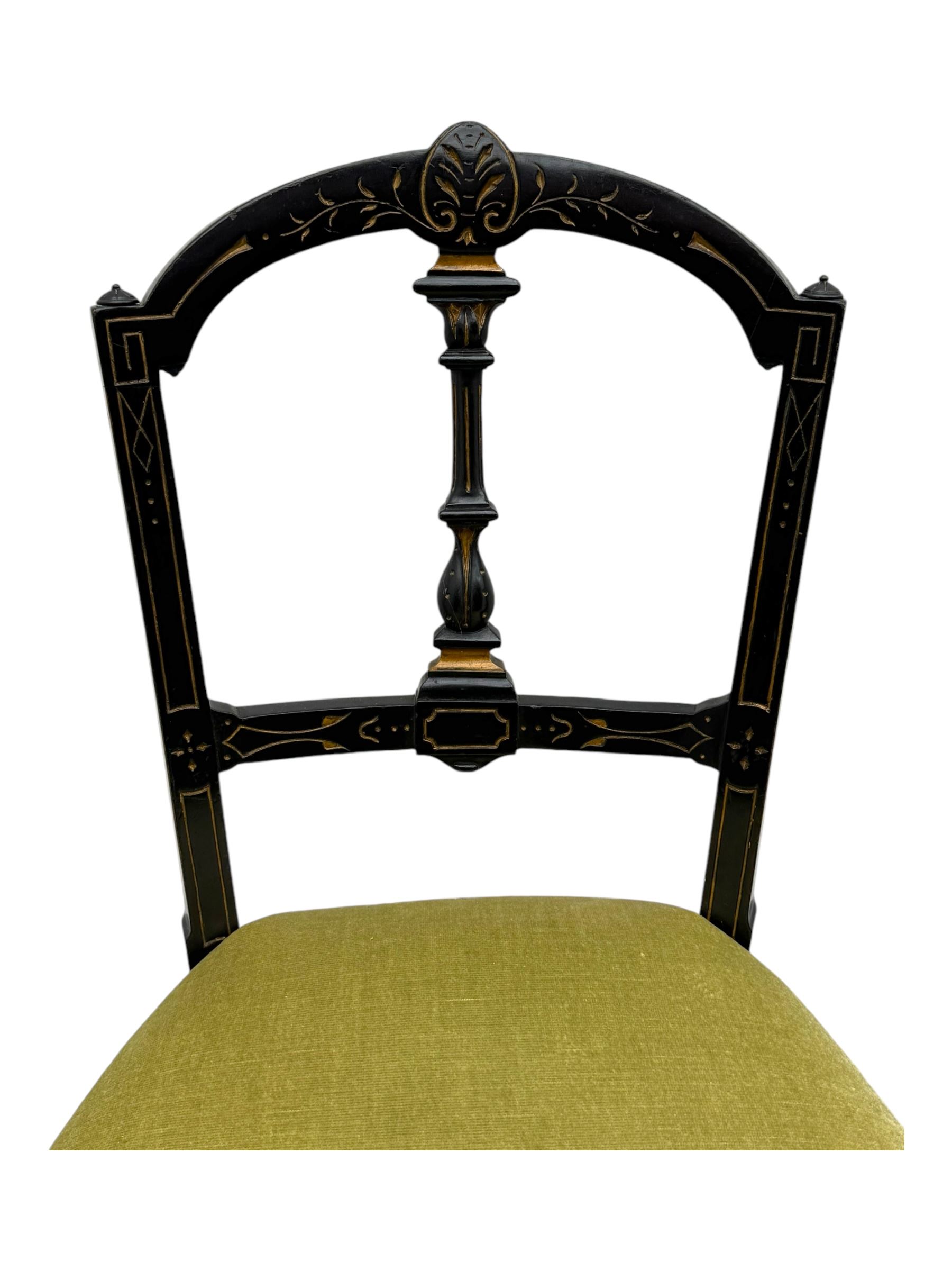 Set of four late Victorian ebonised dining chairs, decorated with carved and gilt foliate decoration, upholstered seats, on turned and fluted front supports 