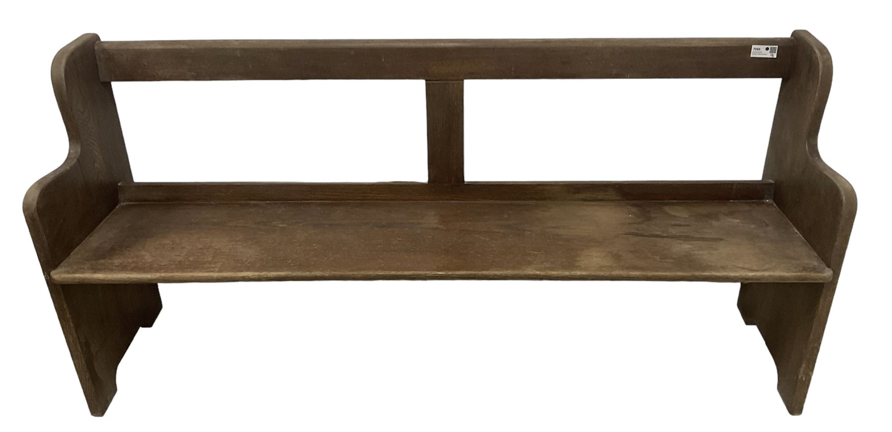 Early 20th century oak church pew or hall bench, open back over single plank seat, on shaped end supports