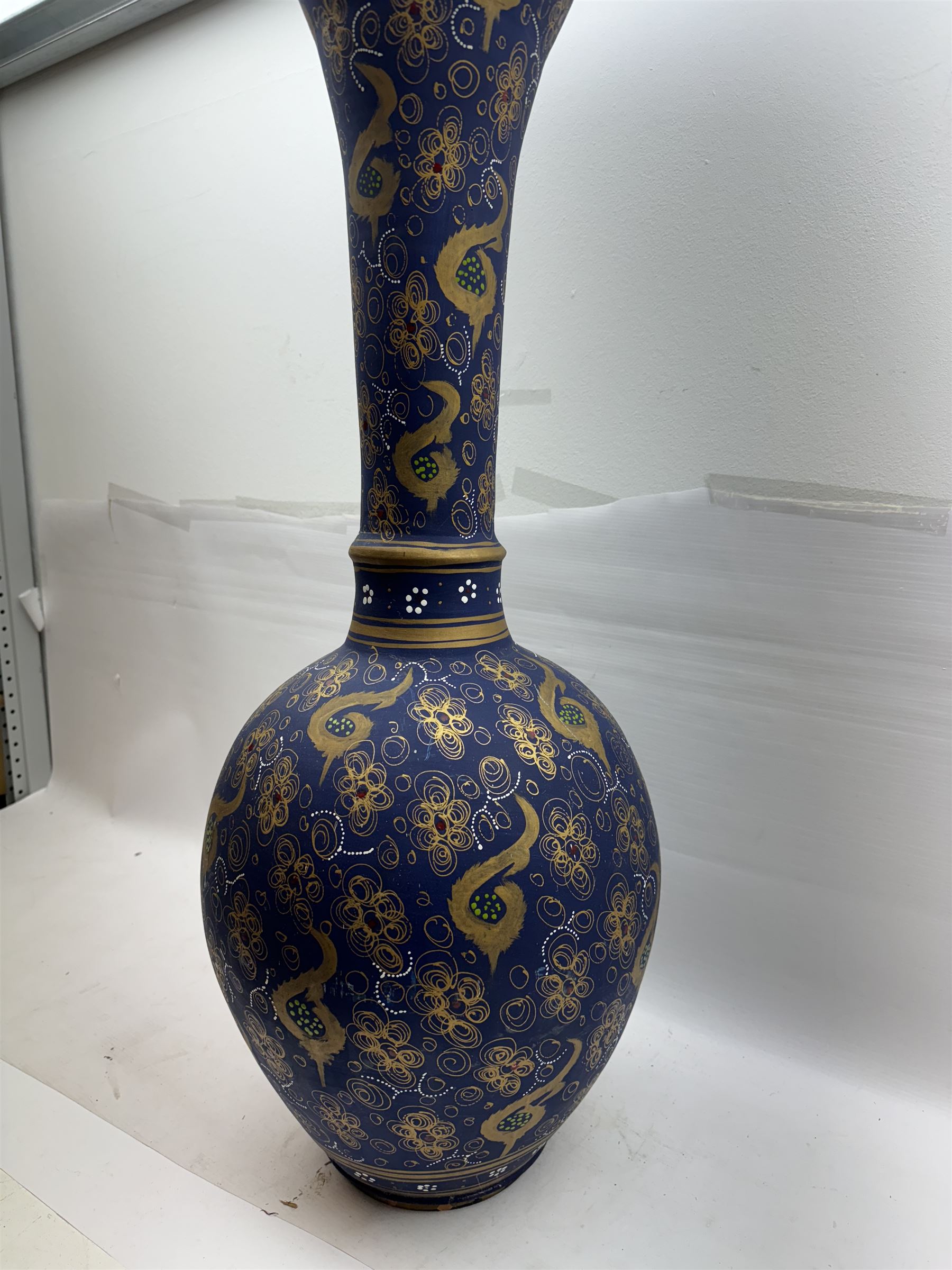 Large and unusual terracotta floor vase, of ovoid form with tall flared neck with frilled rim, decorated with stylised foliate motifs in gilt upon a dark blue ground, H89cm