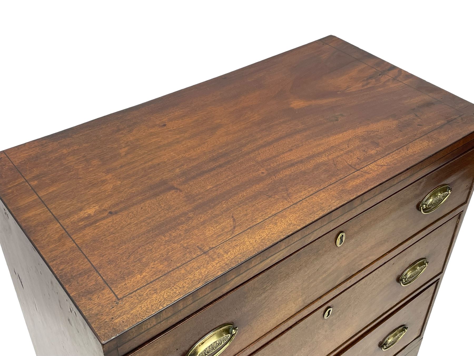 George III mahogany chest, rectangular ebony strung top, fitted with three graduating cock-beaded drawers with oval pressed brass handle plates and demi-lune handles, on tall bracket feet 