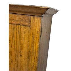 The North of England School Furnishing Company Limited Darlington - early 20th century oak school cupboard, projecting moulded cornice over two panelled doors, fitted with shelves, on chamfered plinth base 