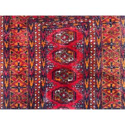 Persian Bokhara dark amber round rug, crimson field with six Gul motifs, surrounded by a guarded border with geometric design (124cm x 70cm); together with another similar in amber and red (101cm x 63cm) (2)