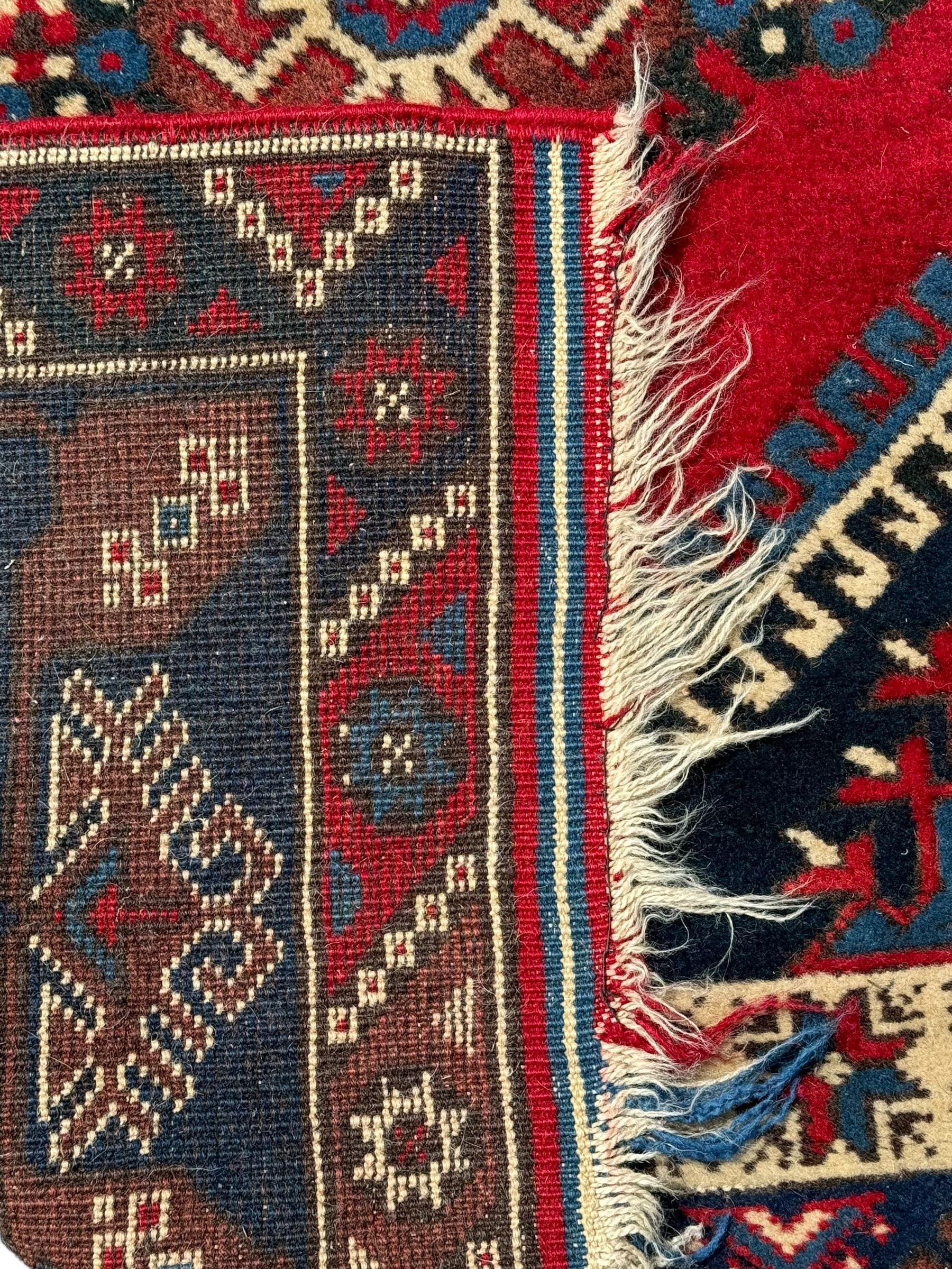 Turkish crimson ground rug, the field decorated with three geometric medallions within a band of star motifs, the main border decorated with stylised plant motifs 