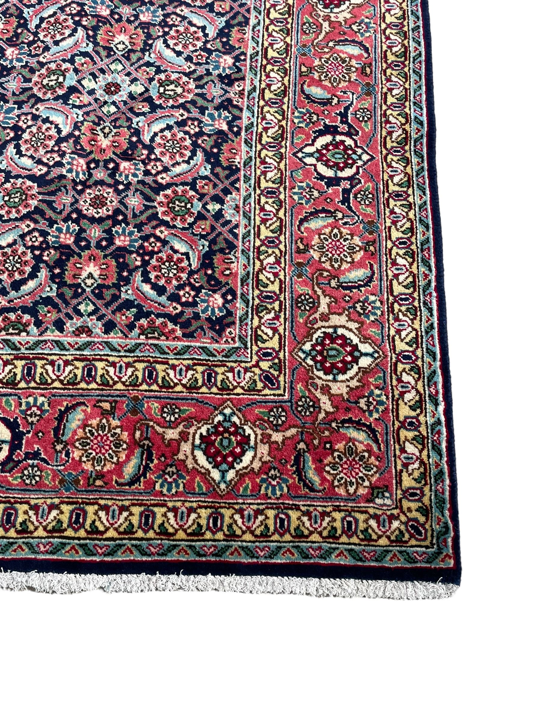 Persian Farahan indigo ground rug, the field decorated with large repeating floral herati motifs, crimson ground border decorated with palmettes and trailing leafy branch, within guard stripes 