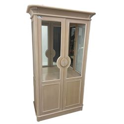 Contemporary display cabinet, moulded cornice above glazed panelled doors with central carved sunburst handles, mirrored back interior with lighting, lower enclosed storage compartment, raised on plinth base