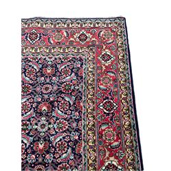 Persian Farahan indigo ground rug, the field decorated with large repeating floral herati motifs, crimson ground border decorated with palmettes and trailing leafy branch, within guard stripes 