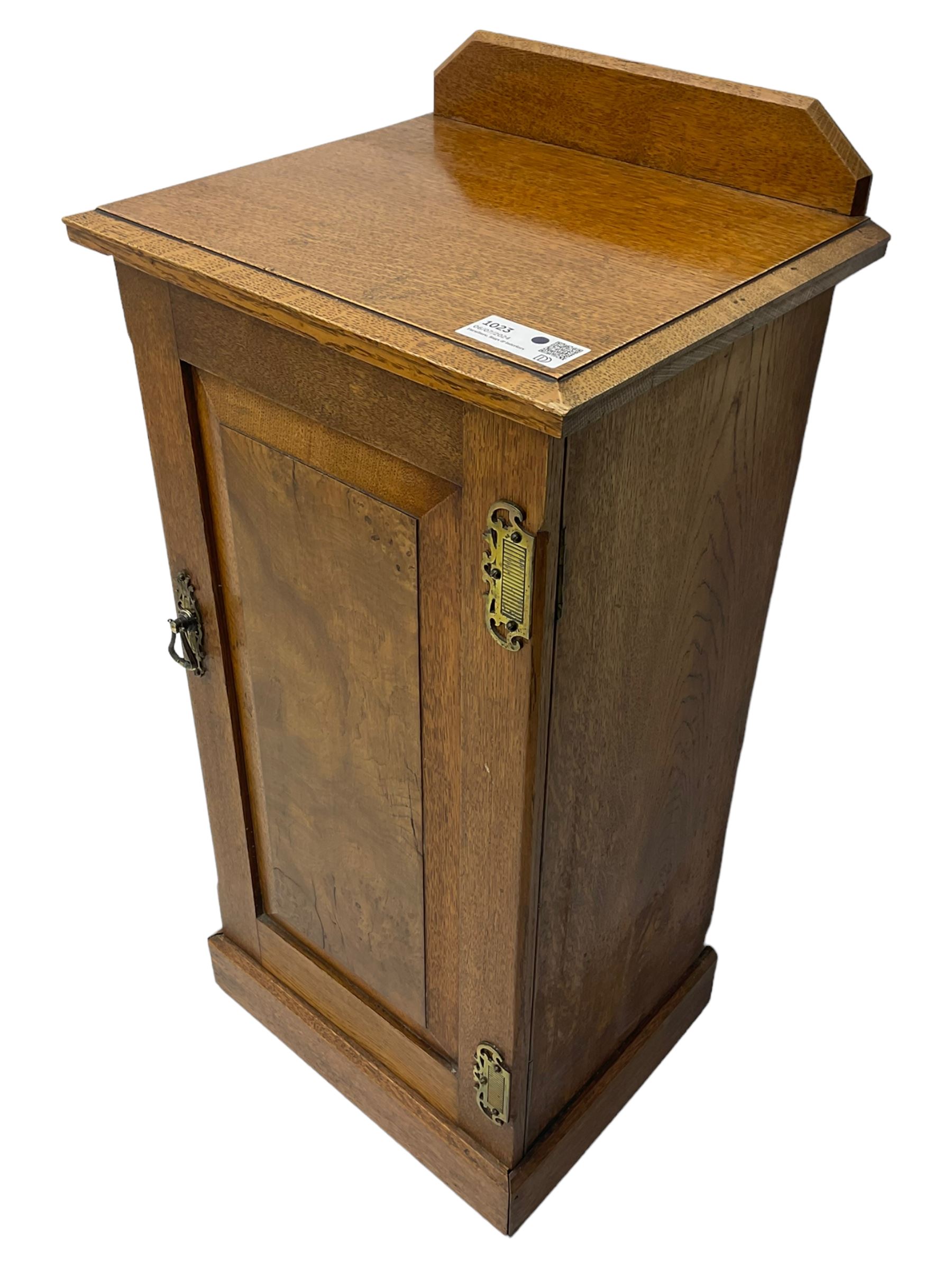 Edwardian oak bedside cabinet, raised back over moulded top, enclosed by panelled door, the interior fitted with shelves, on chamfered plinth base 