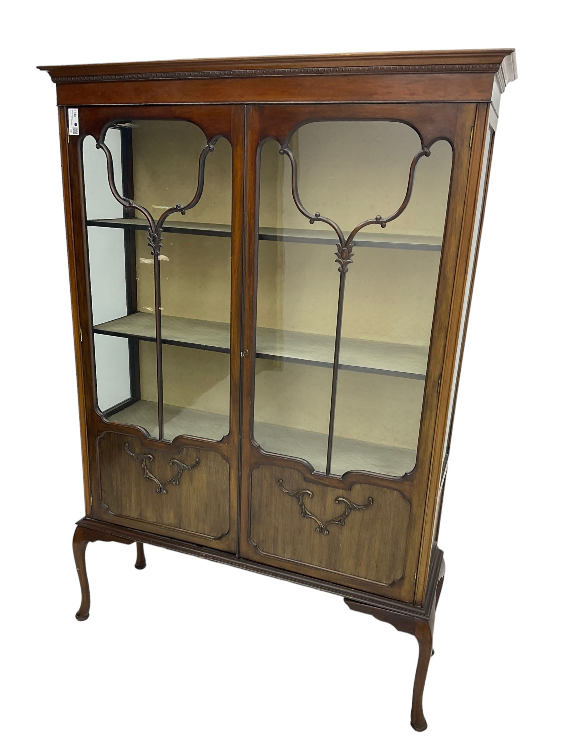 Early 20th century mahogany straight-front display cabinet, projecting moulded cornice over two astragal glazed doors with lower panels, on cabriole supports 