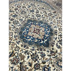 Persian Nain ivory ground carpet, the field decorated all over with leafy branches and stylised flower head motifs, blue ground central medallion and matching spandrels decorated with trailing foliate pattern, repeating guarded border with overall floral design