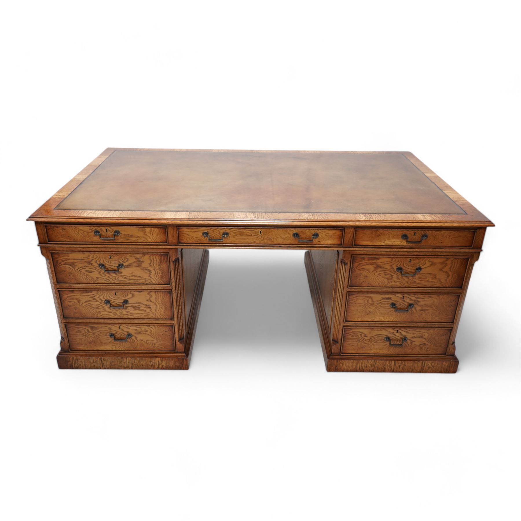 Georgian design figured oak twin pedestal desk, moulded rectangular top with brown leather inset, fitted with nine graduating cock-beaded drawers, canted corners with fluted decoration, on moulded plinth base 