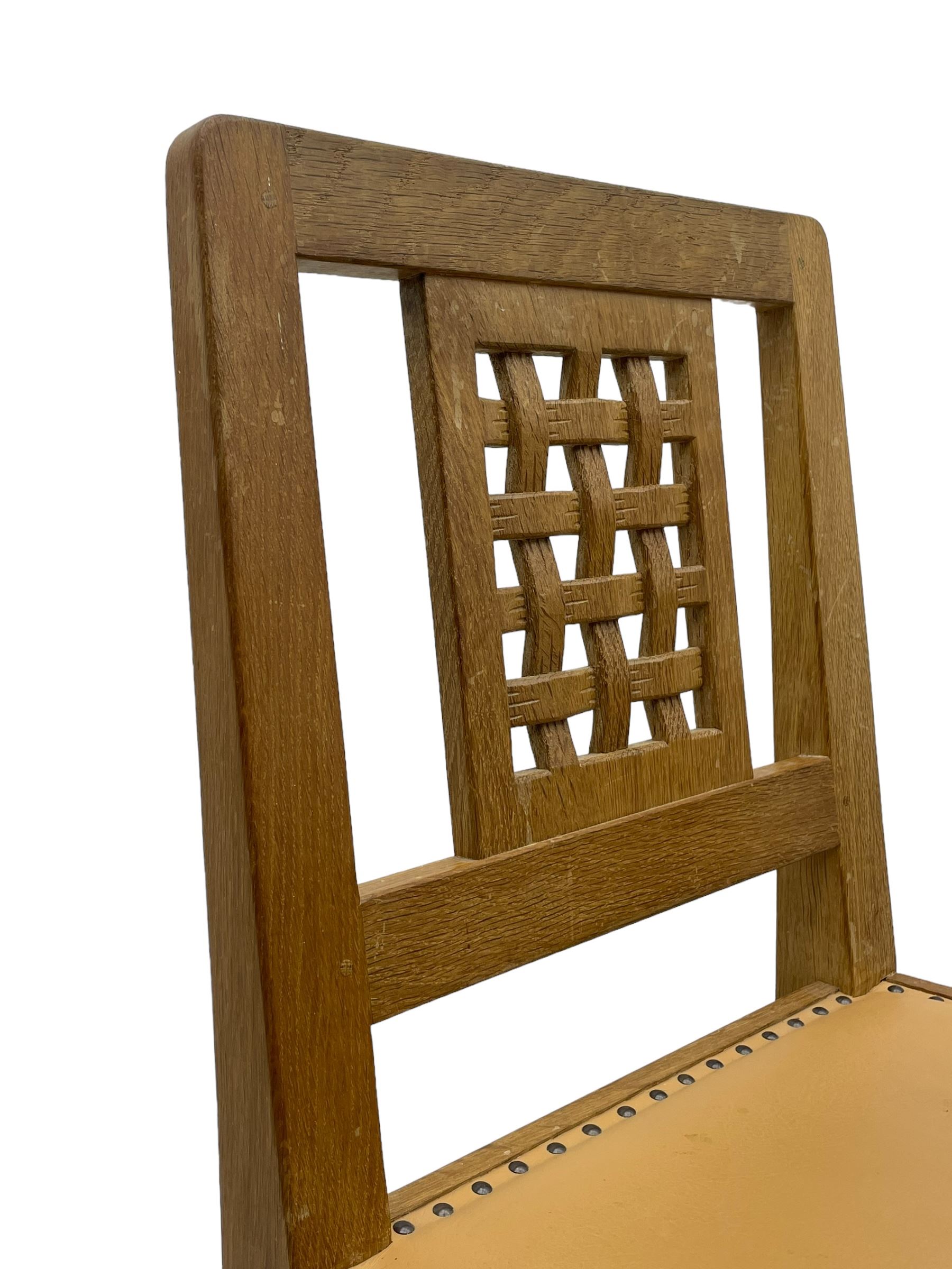 Mouseman - set of six oak dining chairs, pierced and carved lattice panel back over tan leather seat with studded band, on octagonal front supports united by plain H stretchers, carved with mouse signature, by the workshop of Robert Thompson, Kilburn 