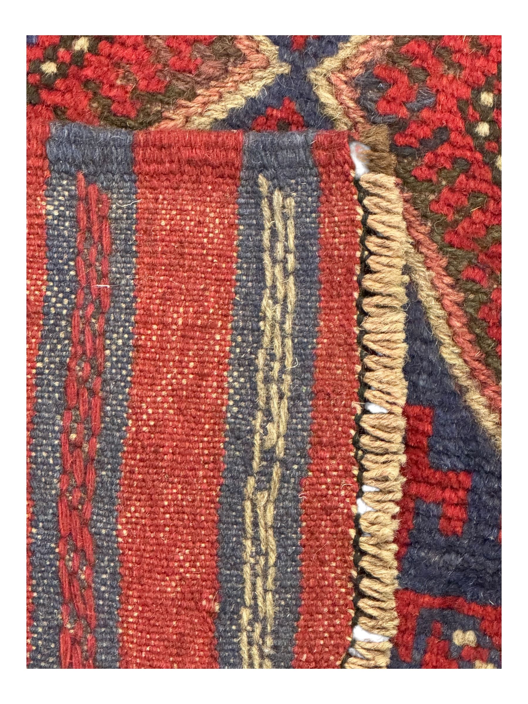 Pashtun Meshwani ground runner, central field decorated with rows of multicoloured diamond medallions, surrounded by geometric motifs, wide red and blue striped border with additional guard bands