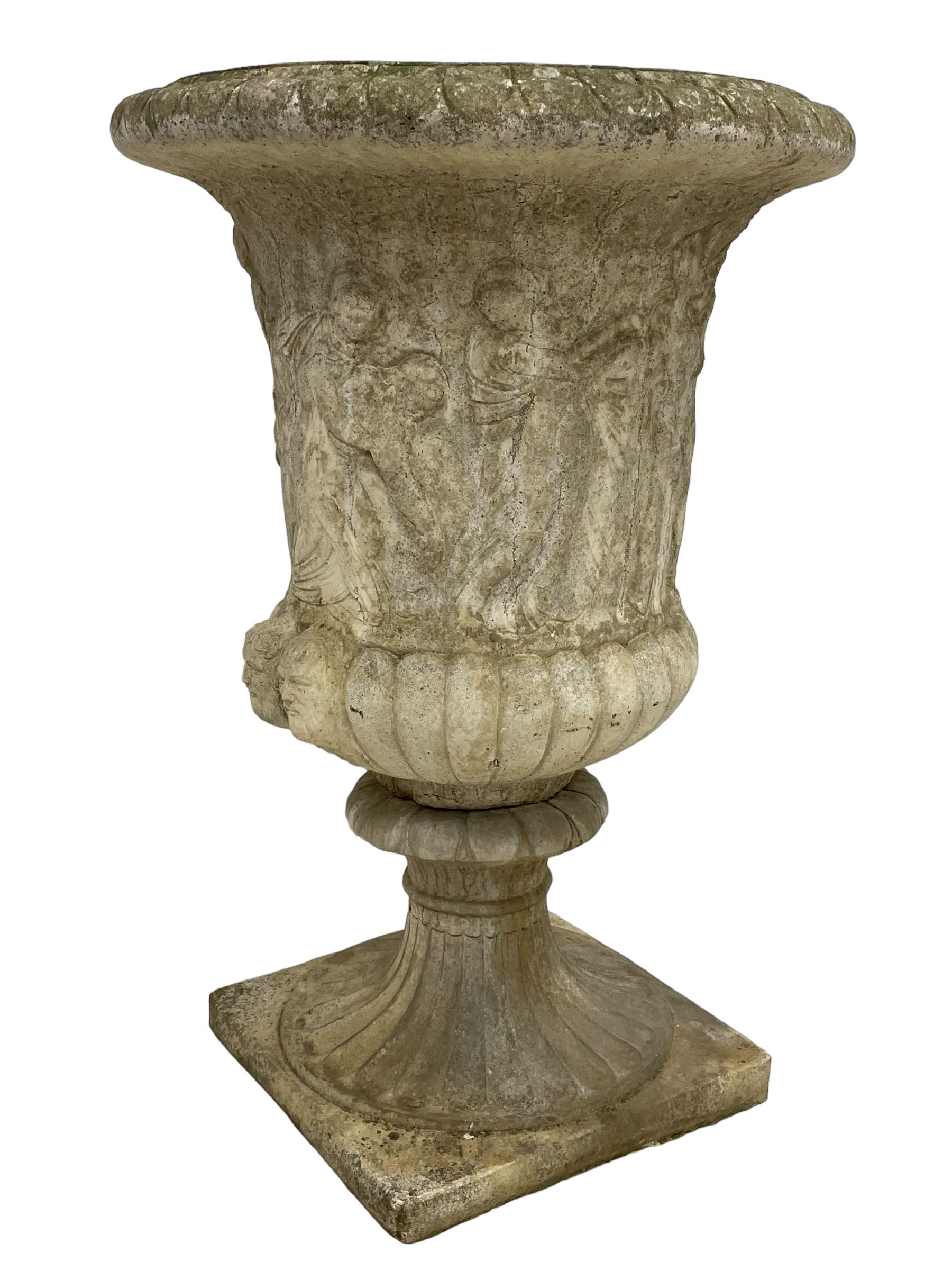 Cast stone Campana shaped urn, decorated with festival scenes over gadrooned underbelly, circular foot on square base