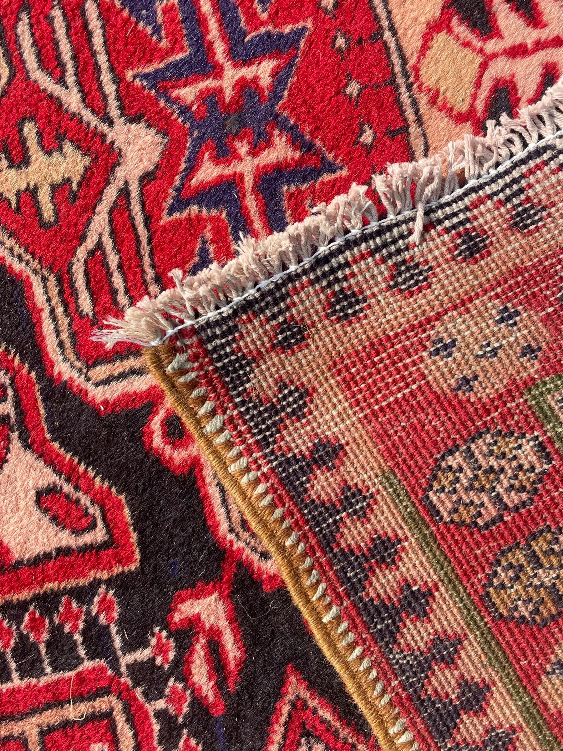 Persian Hamadan indigo and crimson ground rug, the field filled with three shaped medallions, overall geometric design, decorated with sandikli and hac motifs, geometric main border with repeating hooked motifs, within guard stripes decorated with small flower heads, outer crenelated fence band 