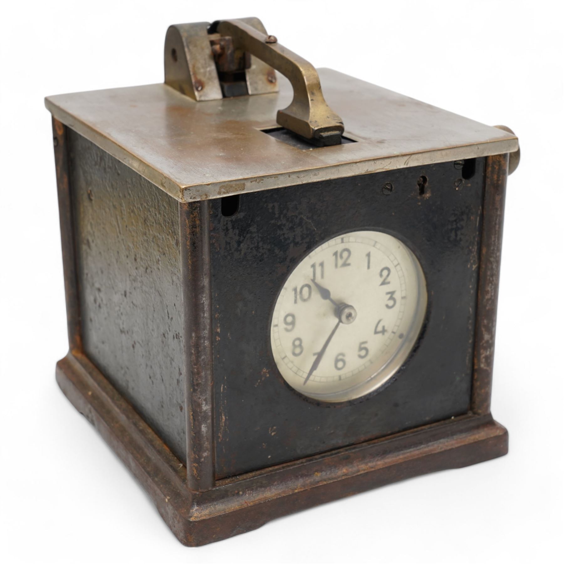 Early 20th century- Pidgeon clock, cast steel case with a silver finished lid and cast brass fittings, glazed circular dial with Arabic numerals, minute track and steel spade hands, spring driven balance escapement. No Keys.