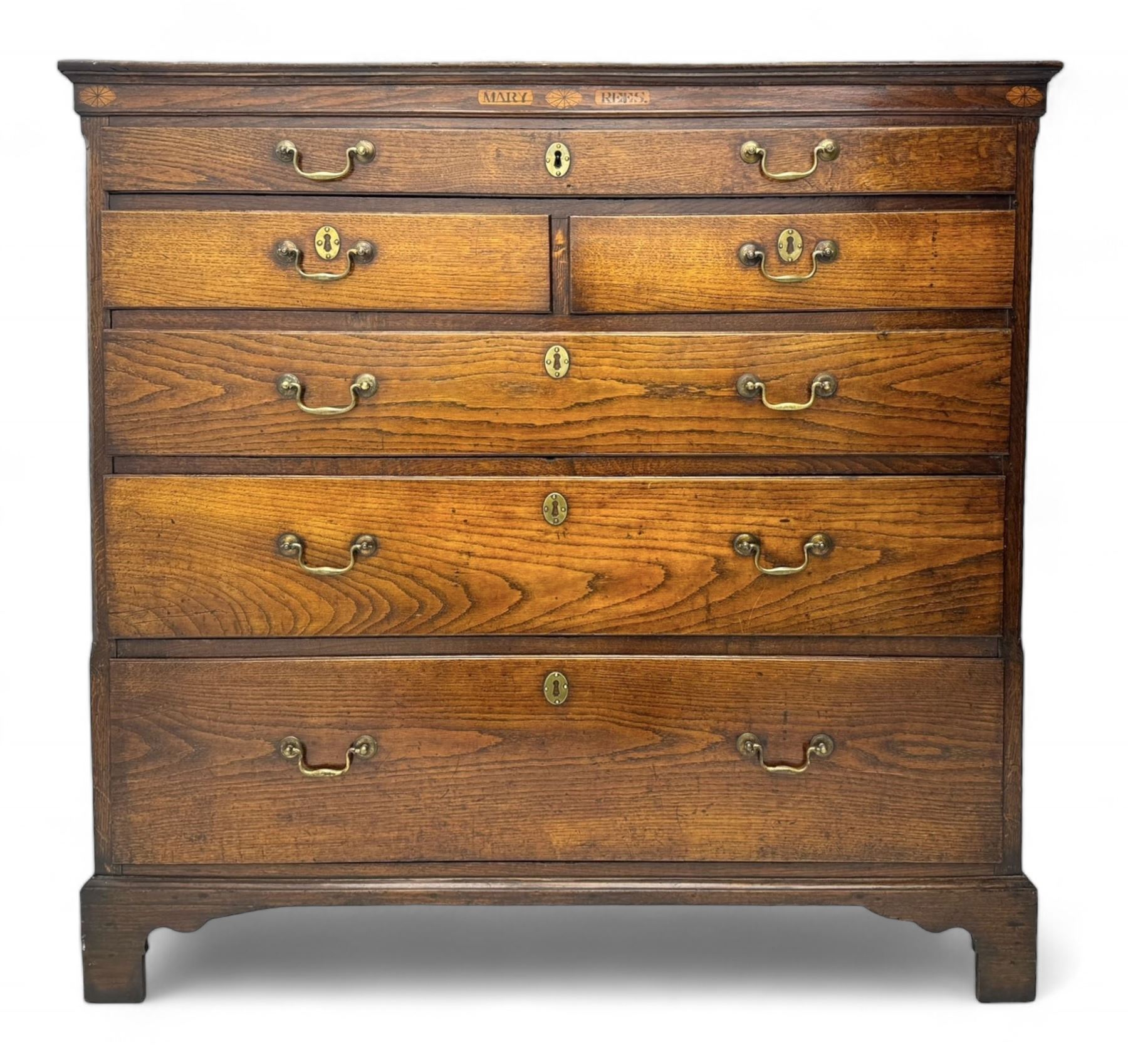 George III oak chest, rectangular top over frieze with inlaid with inscription panels 'Mary Rees' and fan motifs, frieze drawer over two short and three long graduating drawers, fitted with brass swan-neck handles and oval escutcheons, on bracket feet