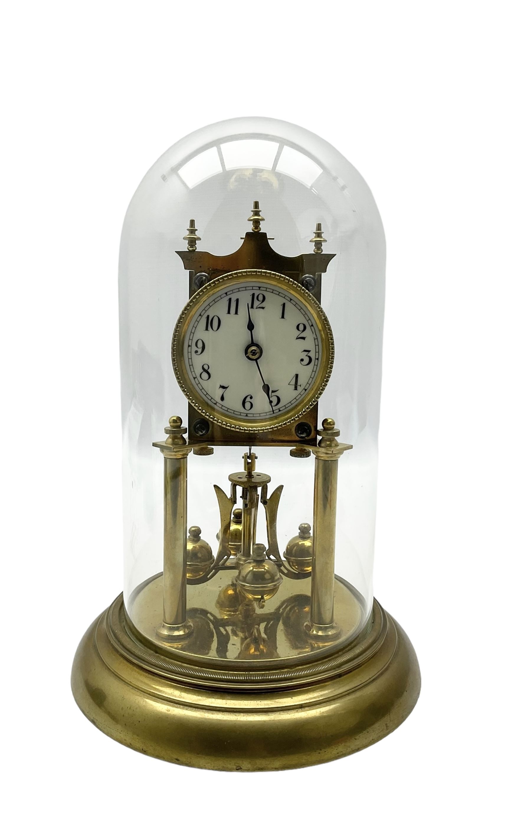 Continental- early-20th century torsion clock under a glass dome, movement raised on two pillars on a circular brass base, with an enamel dial, Roman numerals and spade hands, oscillating four ball circular pendulum. Torsion spring intact.