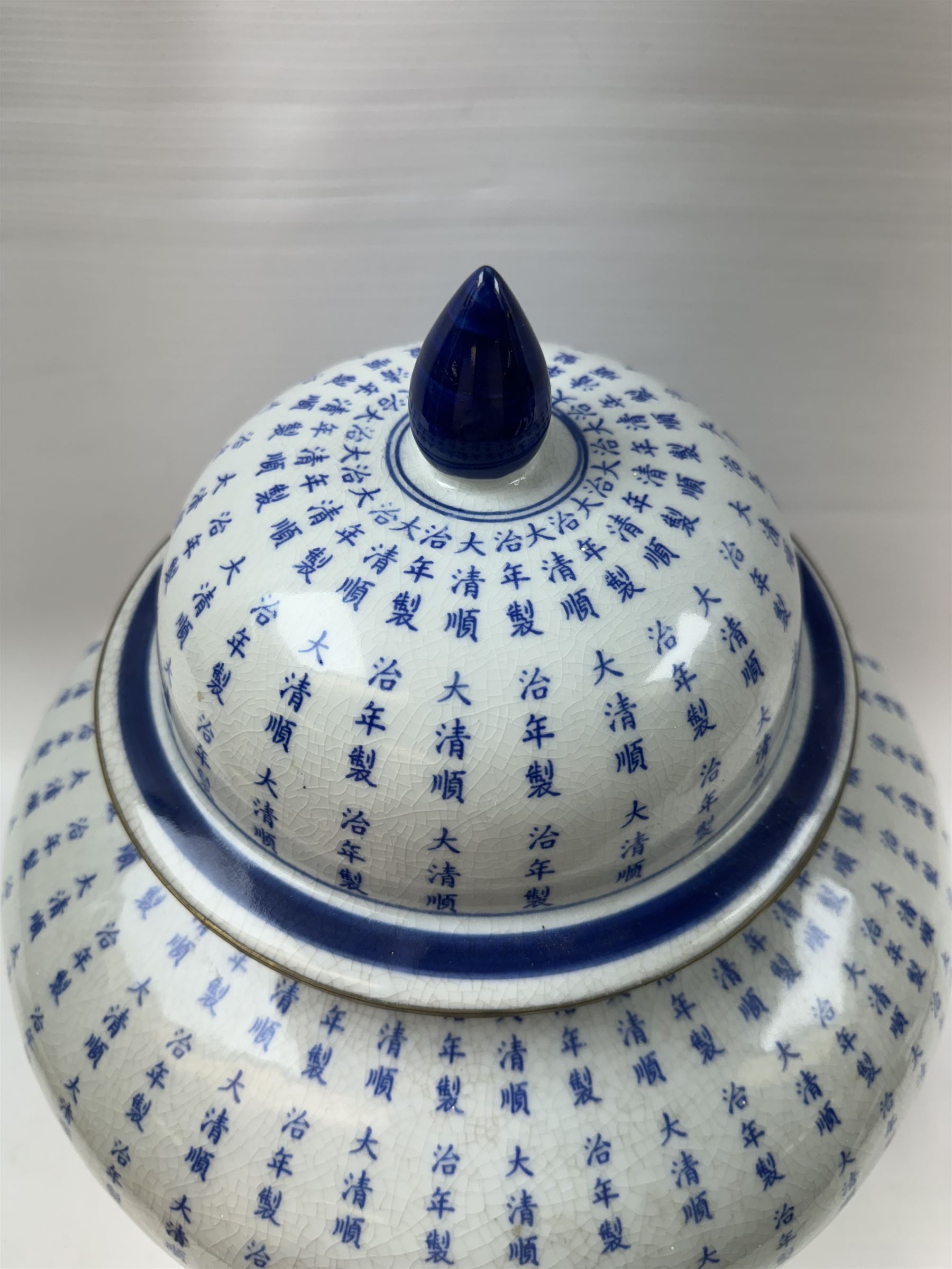 Large Oriental design ginger jar and cover, of squat baluster form with domed cover, decorated in blue with Chinese characters against a white crackle glaze ground, the cover, neck and foot rim with applied brass band, with character mark beneath, H43cm