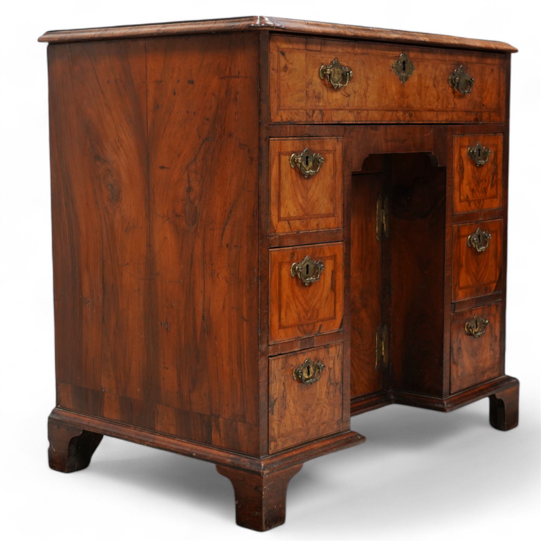 George II figured walnut knee-hole desk, the rectangular quarter-matched veneer top with moulded edge, crossbanding and feathered-banding, fitted with single frieze drawer over three drawers to each side, each with the central recess fitted with a single cupboard enclosing shelf, lower moulded edge on bracket feet