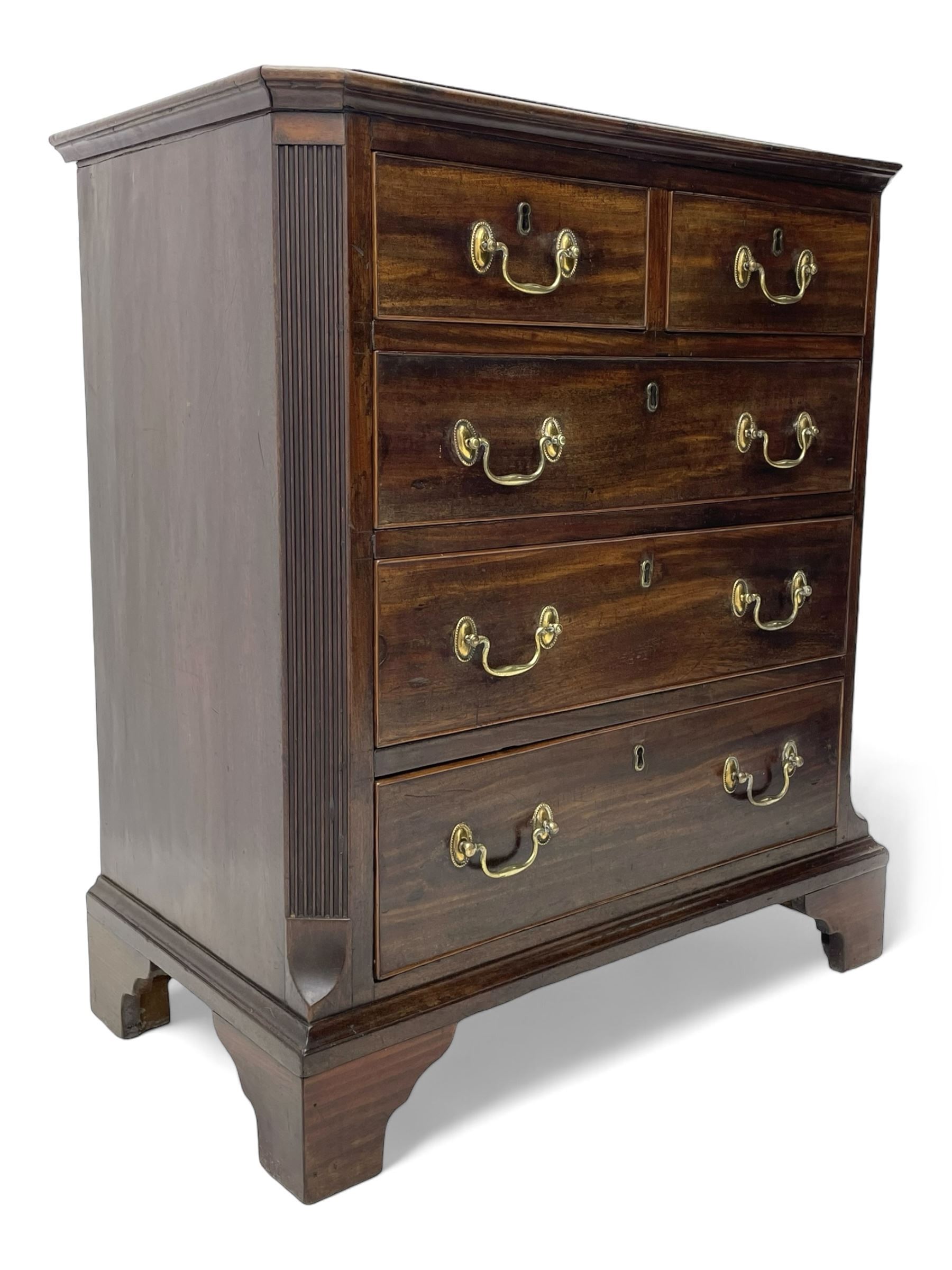 Small George III mahogany chest, rectangular canted form, moulded top over two short and three long cock-beaded drawers, fitted with brass swan neck handles and oval plates, enclosed by fluted upright corners, on bracket feet 