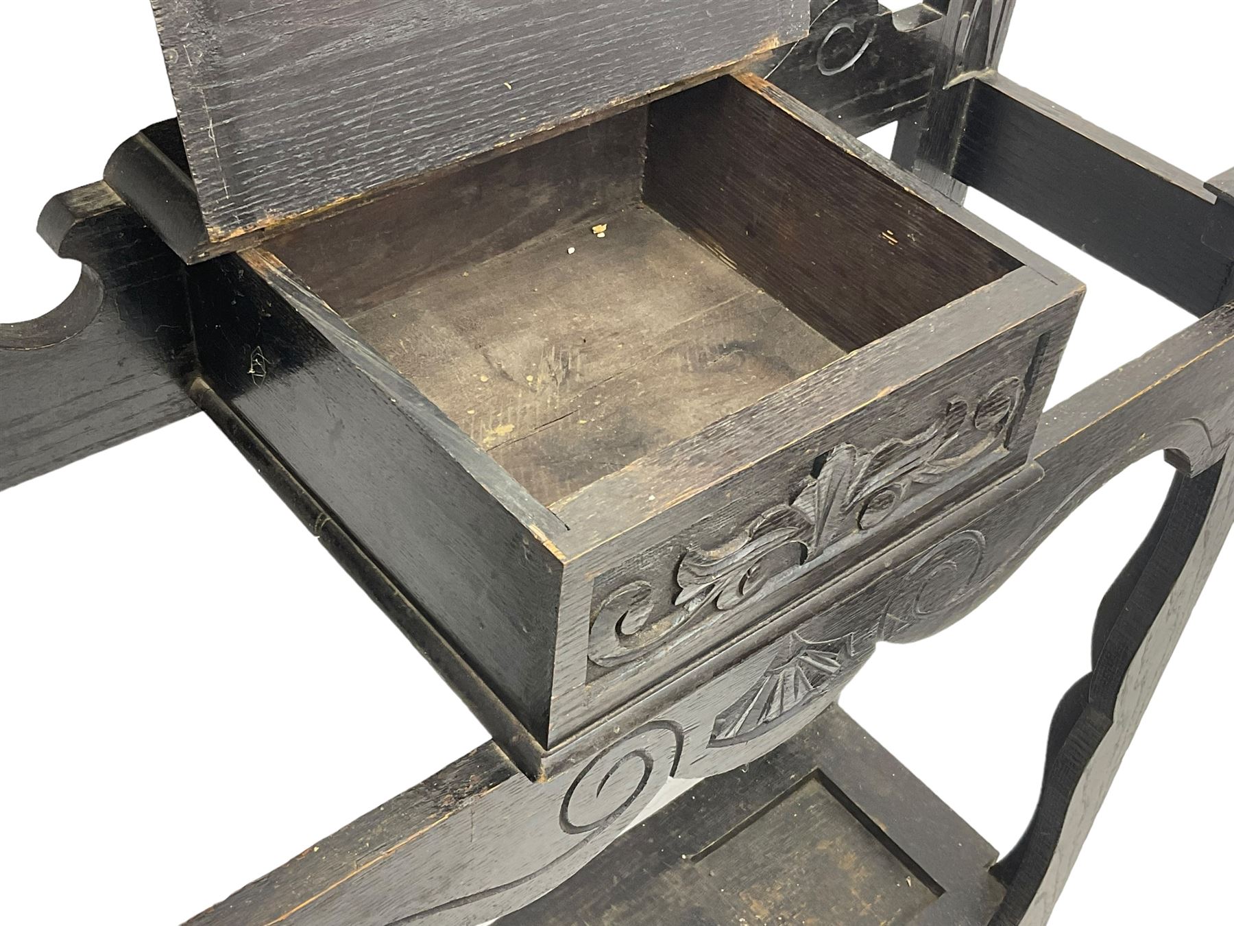 Victorian oak hall stand, the upper section featuring eight brass hooks and central mirror plate flanked by scroll-carved panels, the central section includes a storage box positioned above an umbrella stand, supported by square carved legs with scroll-carved horizontal supports