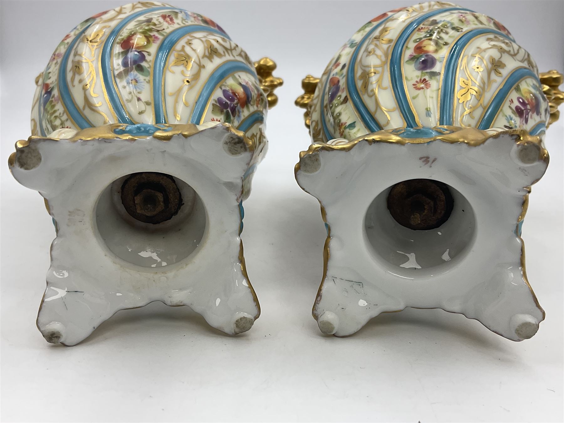 Pair of late 19th/early 20th century Sevres style vases and covers, of baluster form with gilt scroll handles and domed covers, the wrythen fluted bodies decorated with alternating bands of painted fruit and flowers and gilt vines, upon a white and celeste blue ground, with printed and impressed marks beneath, H22.5cm 