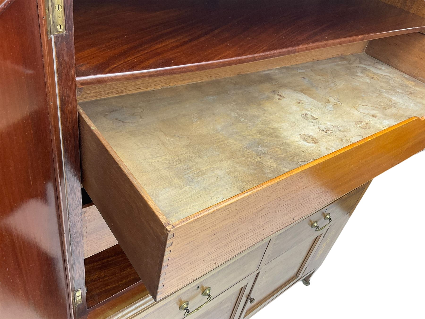 Early 20th century inlaid mahogany cabinet, two-door upper section revealing interior shelving and two large pull-out drawers, the lower section comprises two wide drawers flanked by inlaid floral motif panels above a double-door cupboard, supported by tapering legs with brass castors