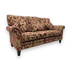 Contemporary upholstered three-seat sofa, scroll arms and loose cushions, embossed beige ground fabric with red and gold floral motifs, on tapered wooden supports