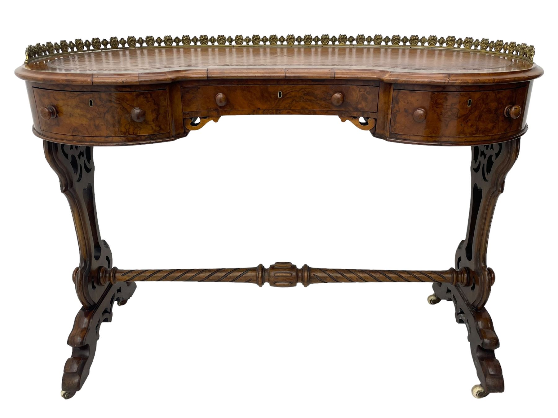 Victorian walnut kidney-shaped writing desk, moulded top with floral cast brass gallery and inset leather writing surface, fitted with three frieze drawers with turned handles, shaped and pierced end supports on raised platforms terminating to splayed feet, united by twist turned and lobe carved stretcher, brass and ceramic castors 