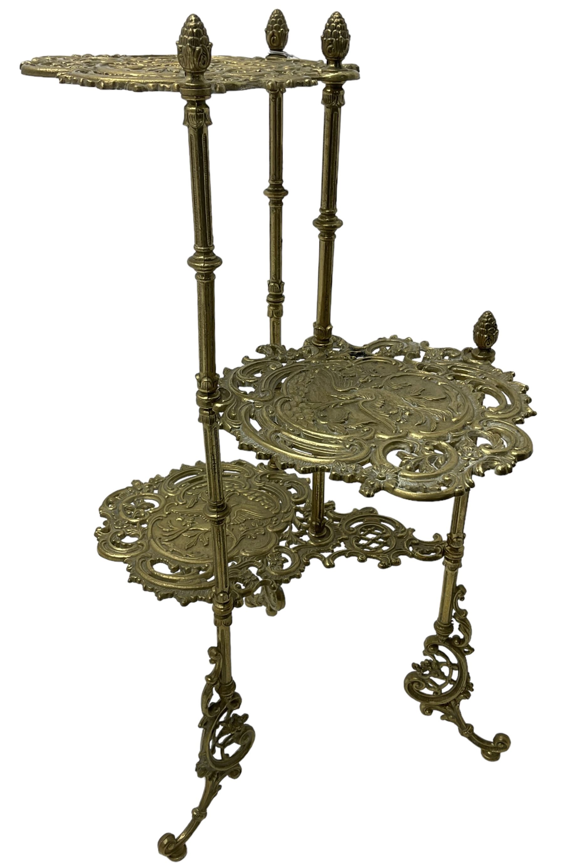 Cast gilt metal three-tier cake stand, each tier decorated with cast foliage scrolls and flower heads with a central bird motif, on turned and fluted supports with splayed C-scroll feet