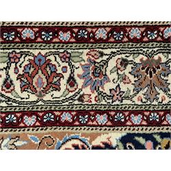 Indo-Persian indigo ground rug, the floral design peach medallion surrounded by trailing and interlaced branches and flower heads, the main border decorated with repeating stylised plant motifs within floral guard stripes 