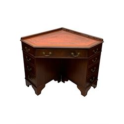 Late 20th century mahogany corner desk, leather inlaid top with gilt tooling, central frieze drawer flanked by two banks of four graduated drawers, raised on shaped bracket supports 