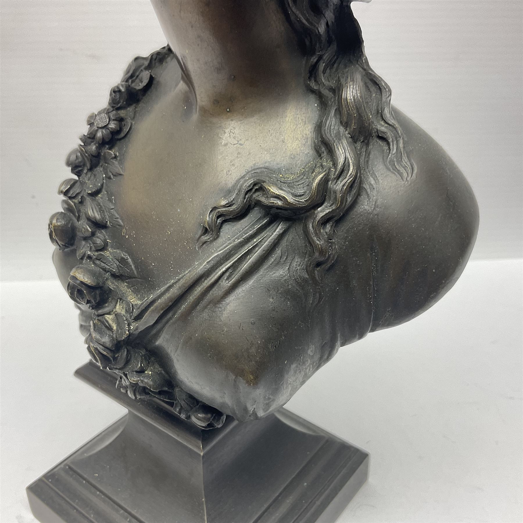 Bronze bust, modelled as a maiden in classical drapery and adorned with floral swags, upon a fluted socle base, overall H23.5cm