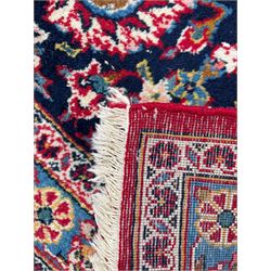 Large Persian Kashan crimson ground carpet, central floral medallion surrounded by swirling leafy branches and palmettes, enclose by floral pattern spandrels, the indigo border with overall scrolling design decorated with palmettes, within guard stripes 