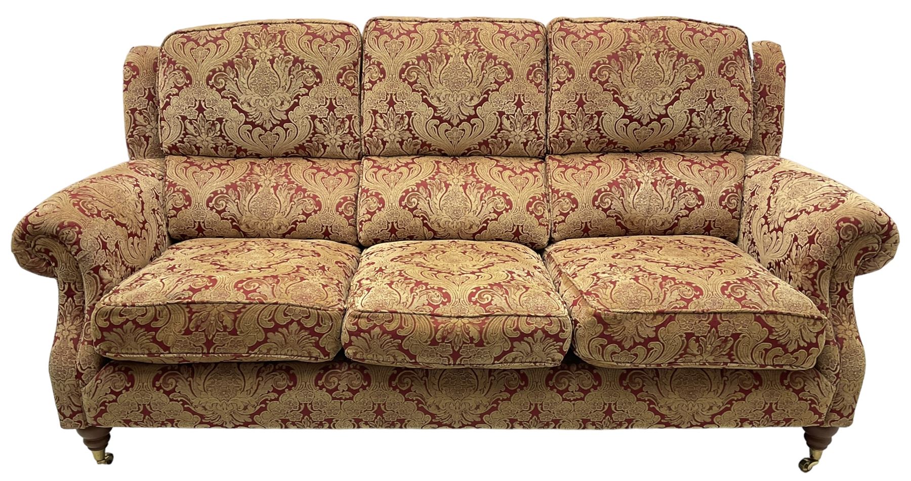 Parker Knoll - three-seat 'Oakham' hardwood-framed sofa, upholstered in red and gold floral pattern fabric, on turned feet with brass cups and castors 