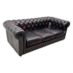 Chesterfield three-seat sofa, traditional shaped upholstered in deeply buttoned dark red leather; together with similar footstool 