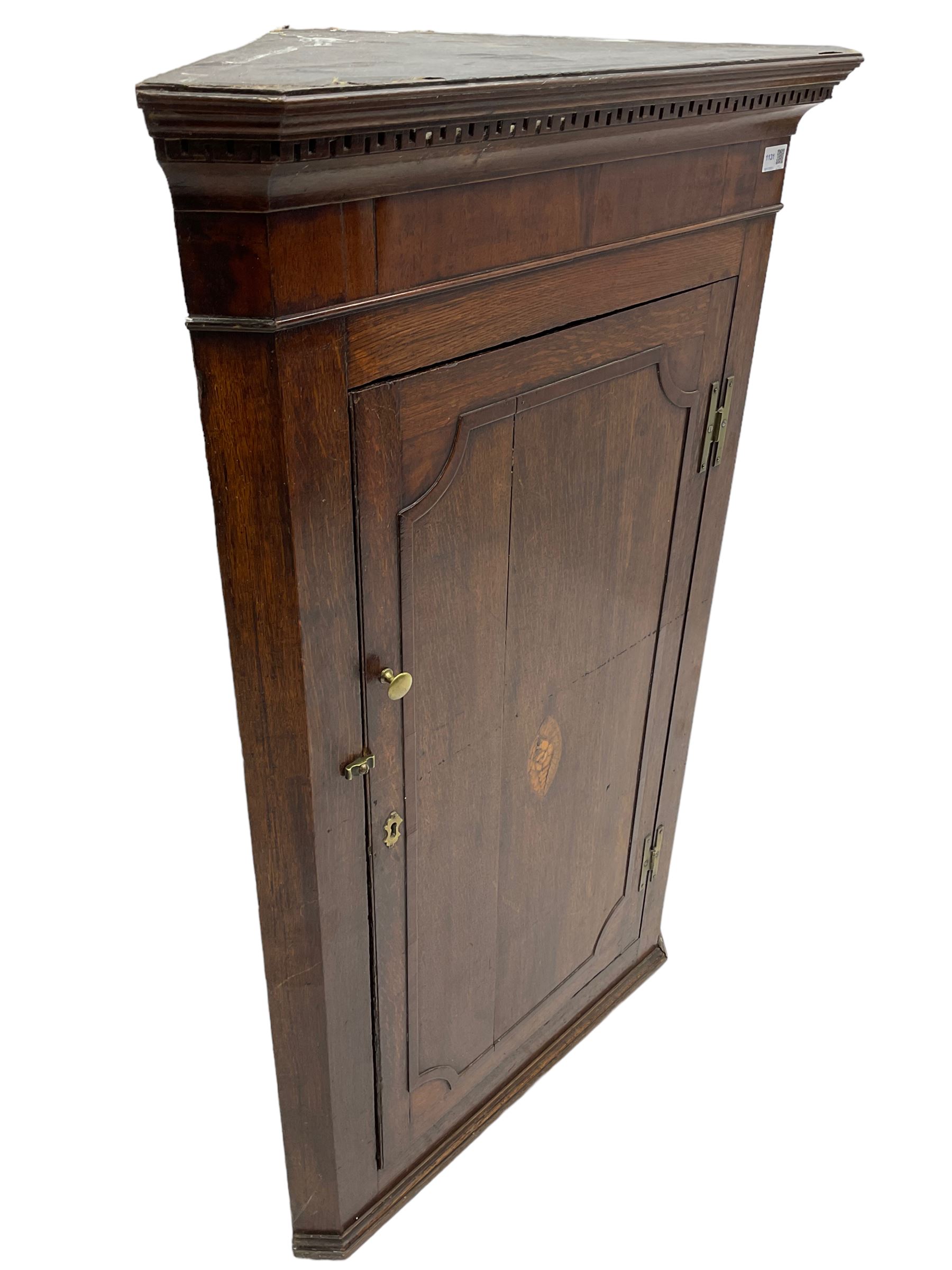 George III oak and mahogany wall hanging corner cupboard, single door decorated with central inlaid shell motif enclosing three shelves