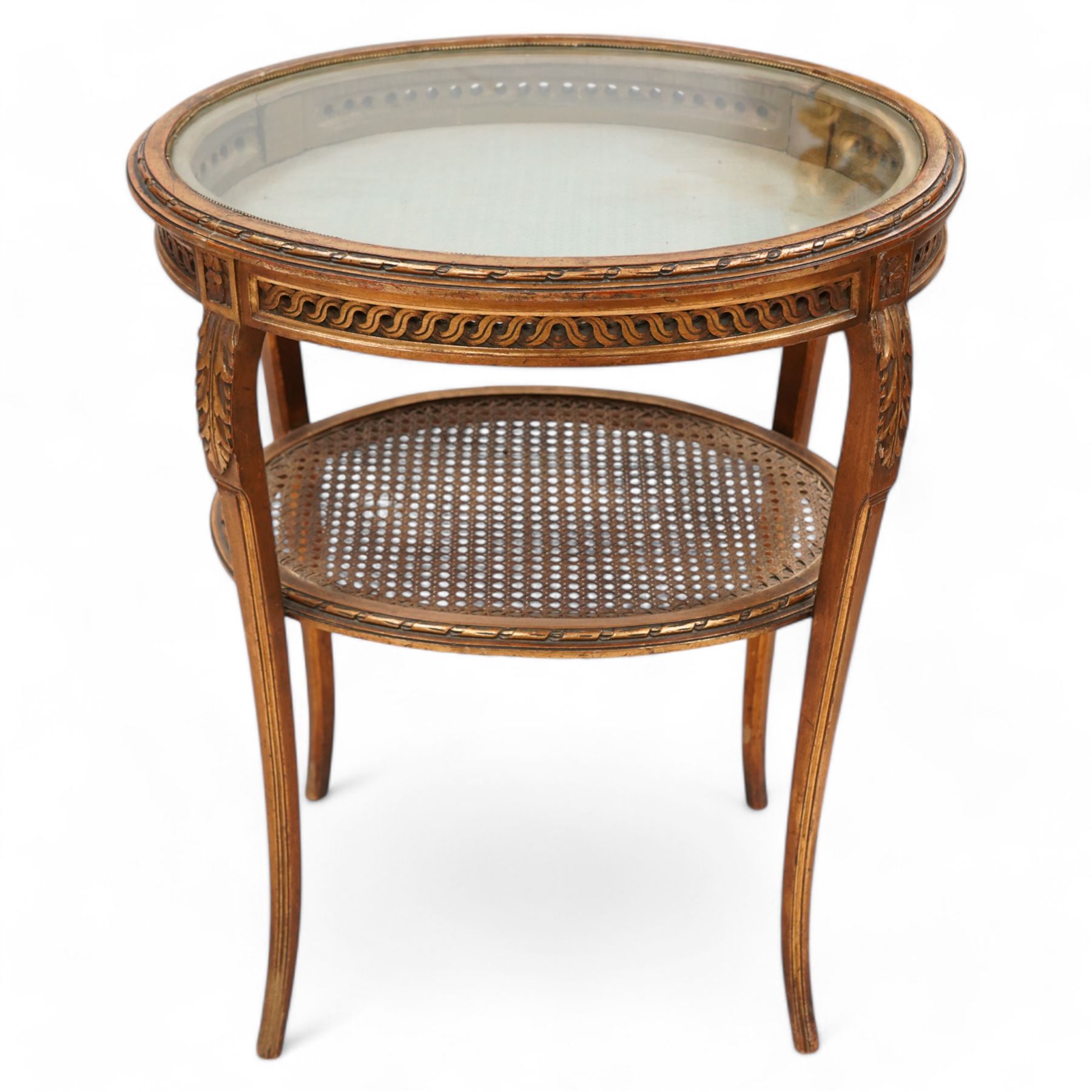 Late 19th century gilt wood bijouterie table, oval form, lift-up glazed lid with ribbon moulded edge, pierced and guilloche carved frieze rails, acanthus carved and moulded cabriole supports united by canework undertier  