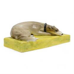 Late 19th century Sampson Hancock Derby porcelain model of a recumbent greyhound wearing a black collar, on a rectangular green painted base, initialled H.W with iron red marks beneath, L13.5cm x H4.5cm